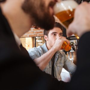 Cropped image of friends drinking beer on bar in cafe